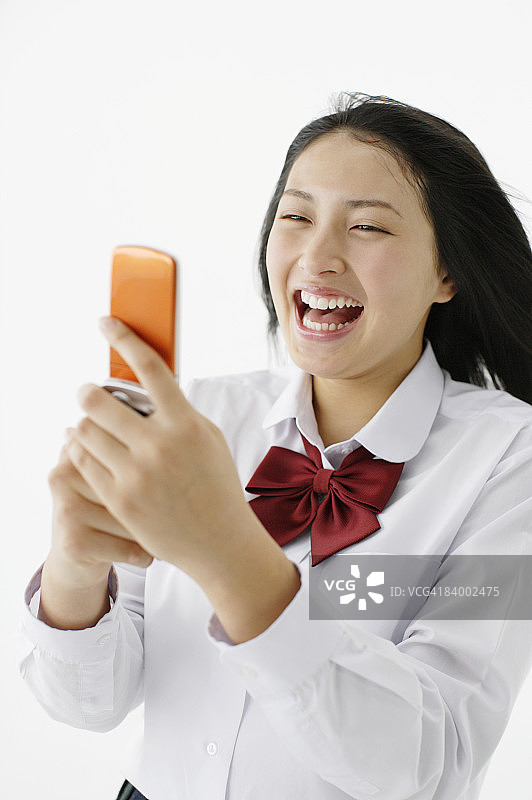 使用手机微笑的女学生，影棚拍摄图片素材