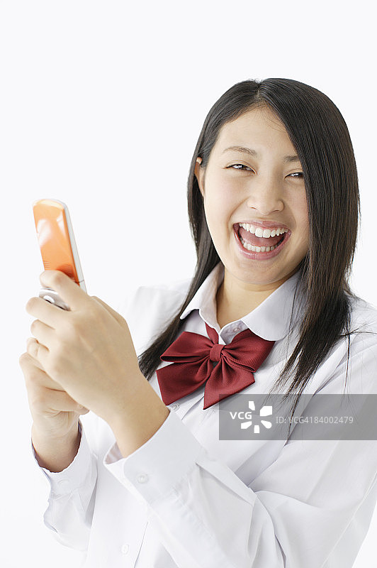使用手机微笑的女学生，影棚拍摄图片素材