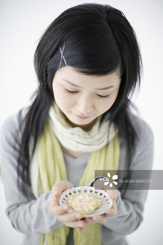 手捧饼干，向下看的少女 портрет，影棚拍摄图片素材