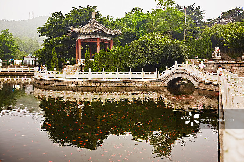 中国山东省青岛湛山寺的桥梁和树木在水中的倒影图片素材