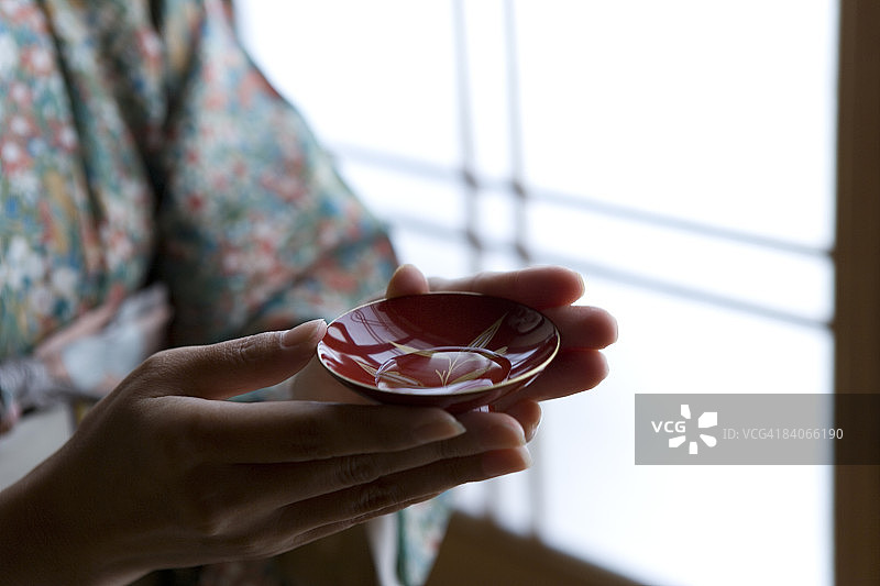 手持漆器清酒杯的女人图片素材