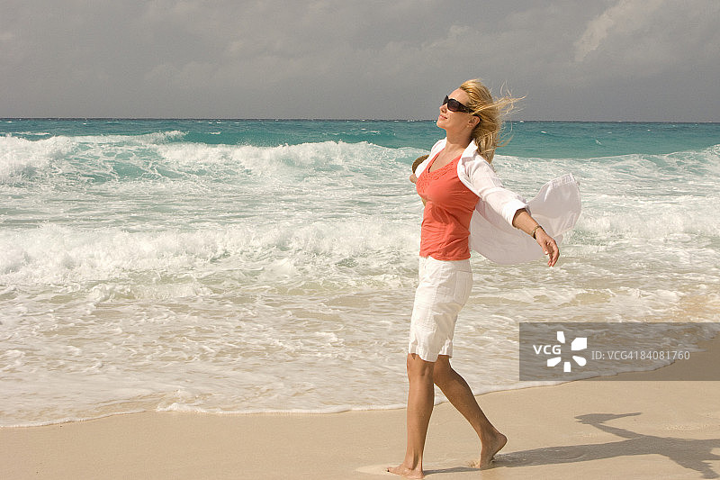 在热带海滩上迎风行走的女孩图片素材