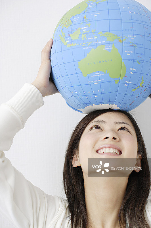 头顶地球仪，面朝上方微笑的女人图片素材