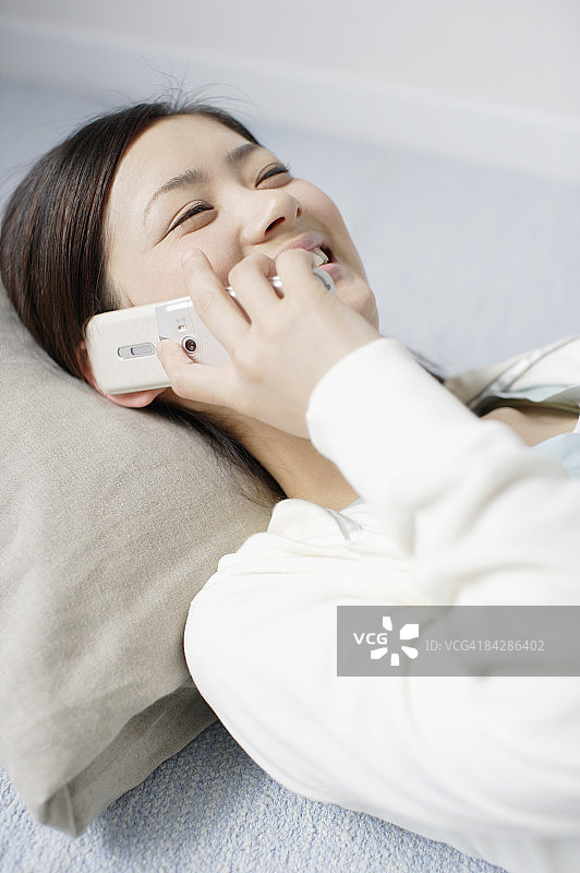 躺在地毯上笑着用手机交谈的女人图片素材