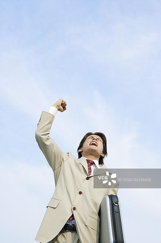 商人对着蓝天挥拳呐喊图片素材