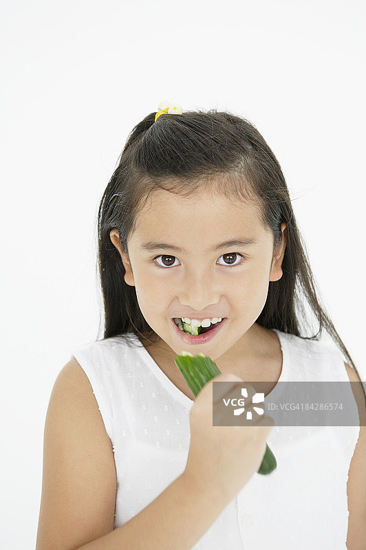 女孩咬一口黄瓜，工作室拍摄图片素材