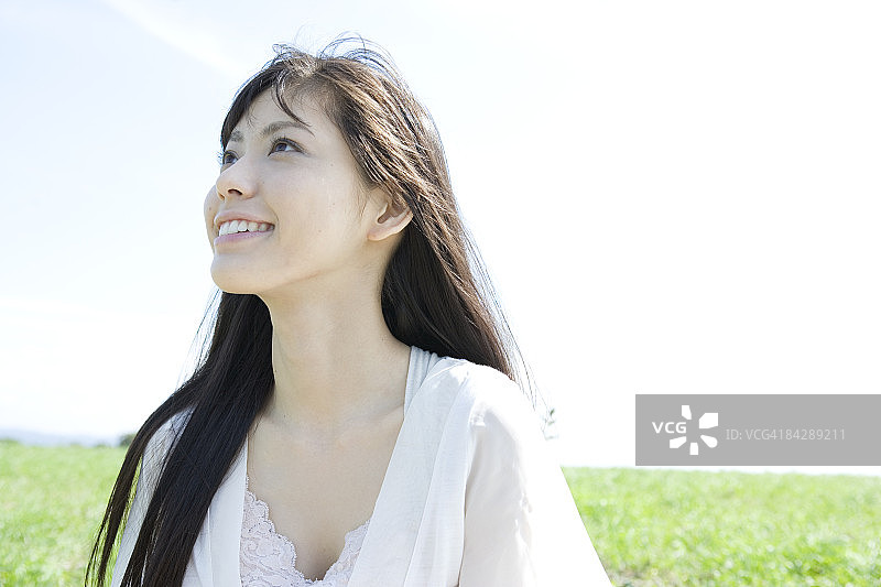 在草地上抬头微笑的年轻女人图片素材