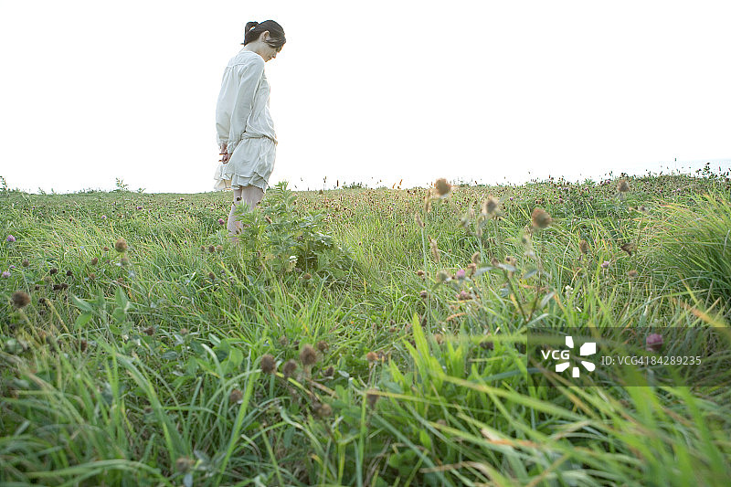 中年妇女站在草地上，向下看图片素材