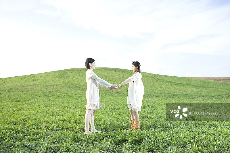 在草地上手牵手面对面的日本女人图片素材