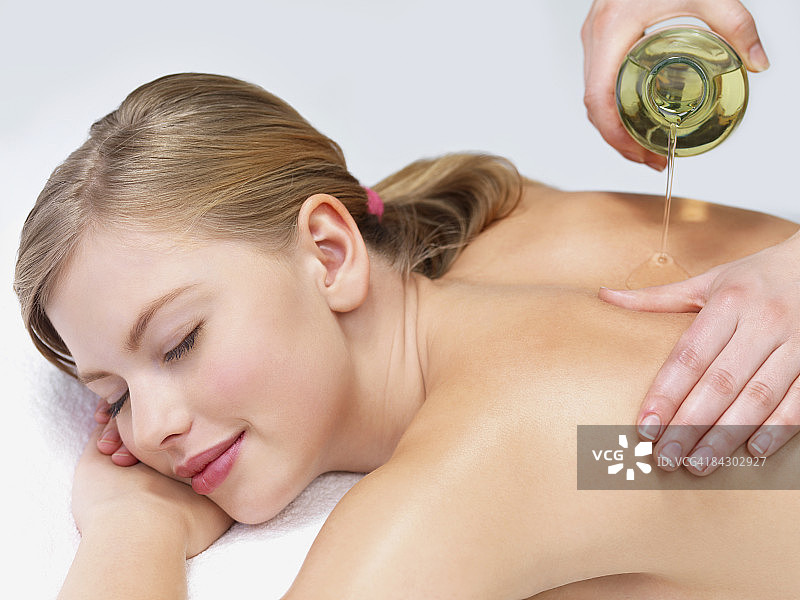 年轻女子接受精油按摩图片素材