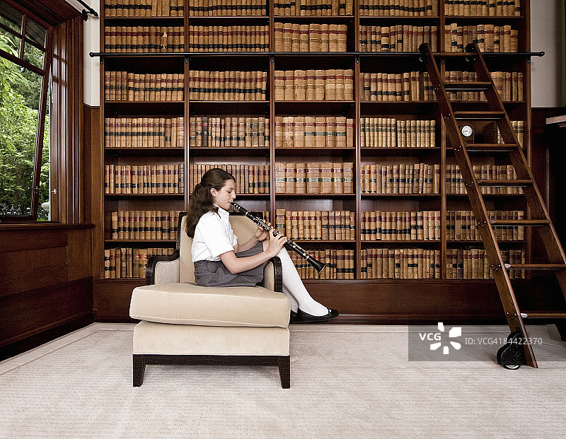 女孩在私人图书馆吹单簧管图片素材