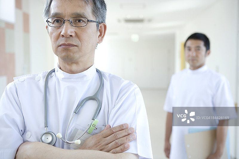 交叉双臂思考的日本男医生图片素材