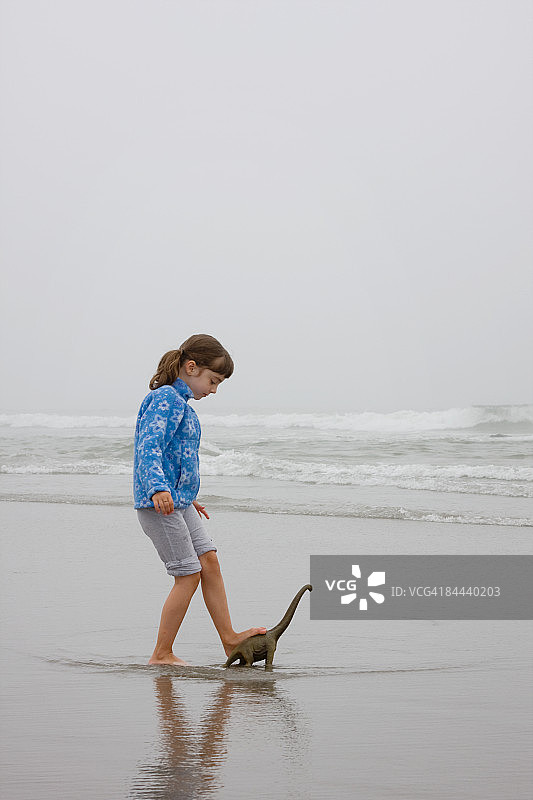 在晨雾中的海滩上，女孩和塑料玩具图片素材
