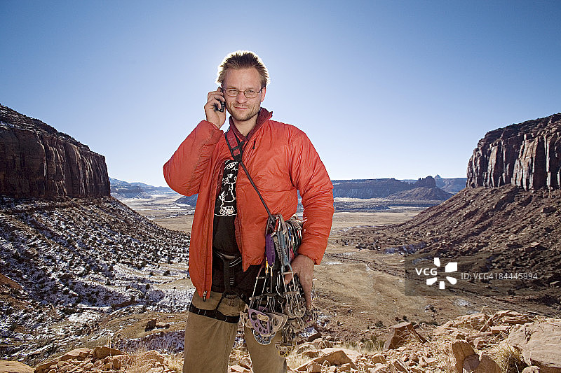 在巨大山谷中使用手机的攀岩者图片素材
