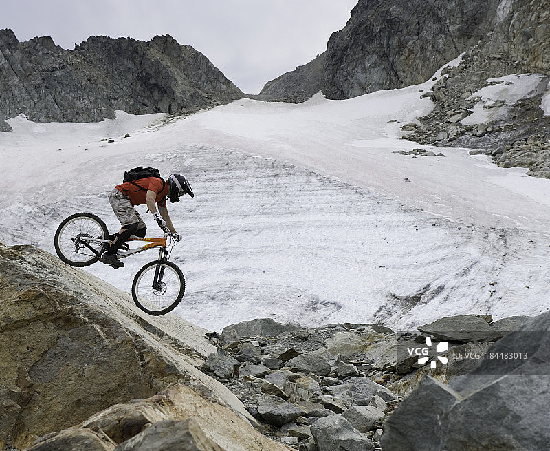 男子在冰川旁骑山地自行车图片素材