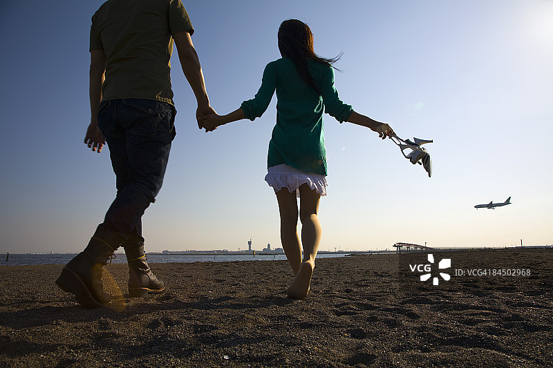 情侣牵手漫步在空旷的沙滩上图片素材