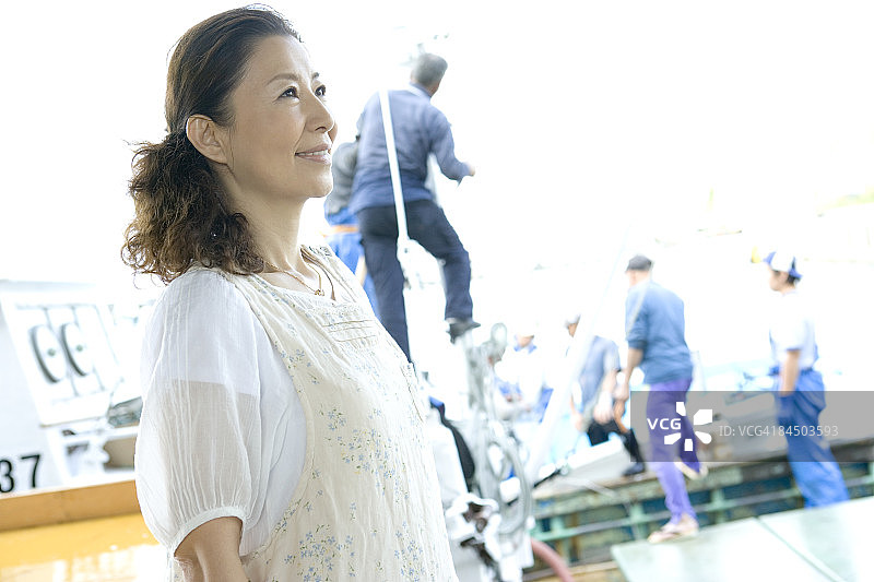 在港口戴着围裙，眺望远方的中年妇女图片素材