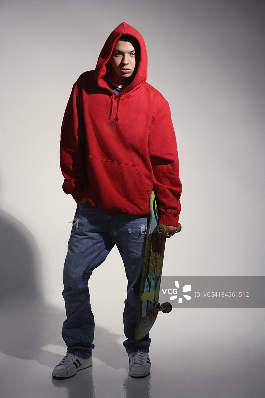 穿着红色连帽衫拿着滑板的年轻男人图片素材