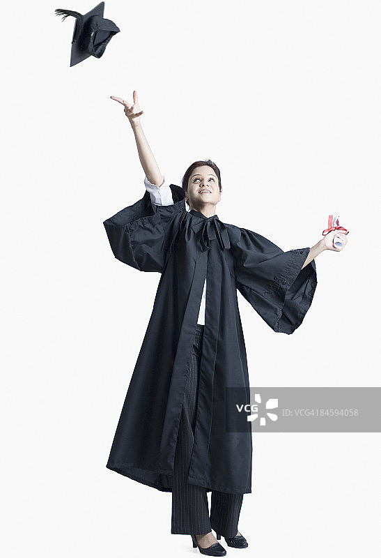 年轻女毕业生将毕业帽抛向空中图片素材
