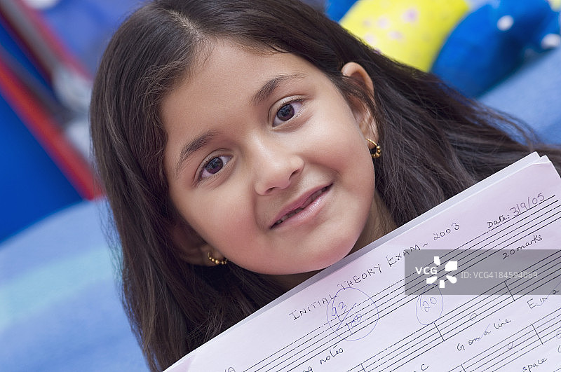 展示她的答卷并微笑的女孩肖像图片素材