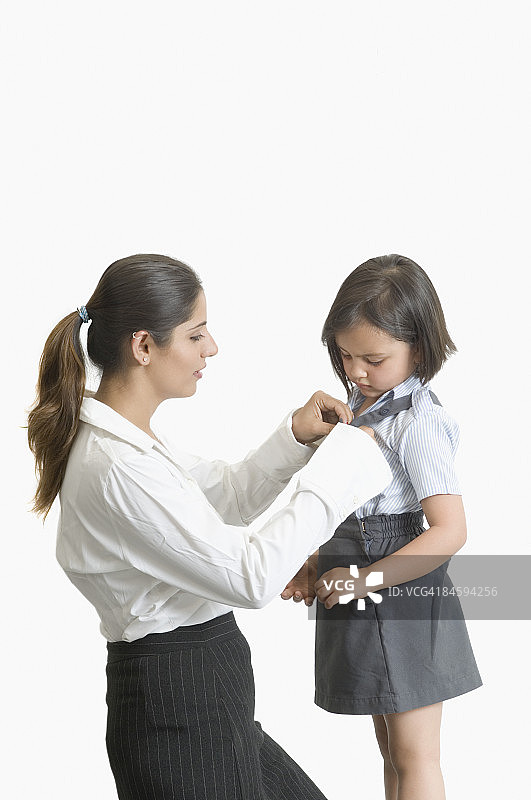 帮助女儿穿校服的年轻女子侧面照图片素材
