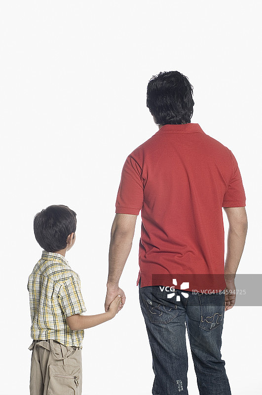 年轻男子与儿子手牵手站立的背影图片素材