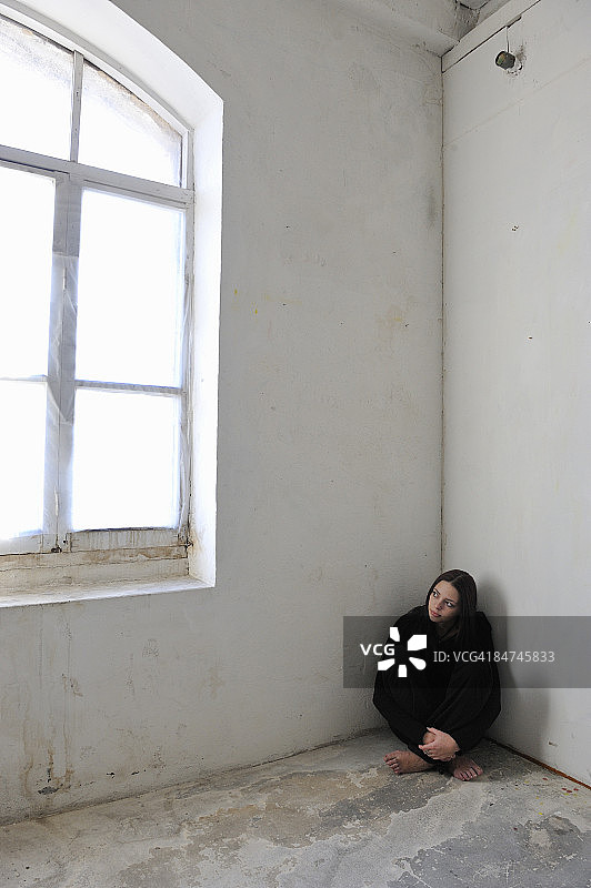 女子坐在房间角落的窗边图片素材