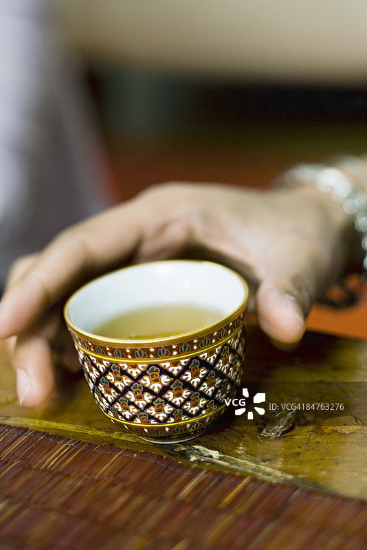 手拿装满茶的彩色茶杯图片素材