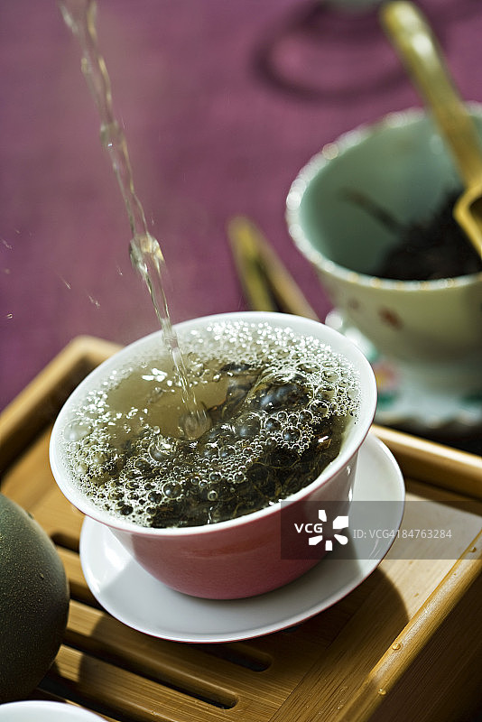 倾倒热水，飞溅在茶杯中的茶叶上图片素材