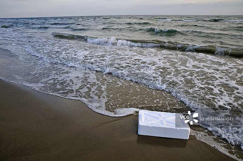 日落时海滩上的聚苯乙烯容器部件图片素材
