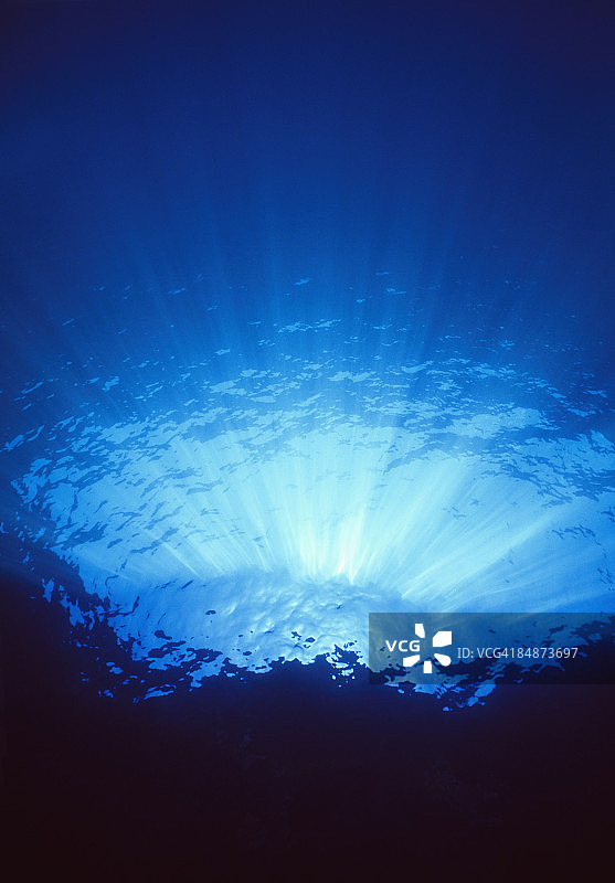 阳光穿透清澈的水面，映照悬崖边图片素材