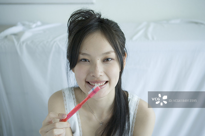 年轻女人拿着牙刷，面带微笑图片素材