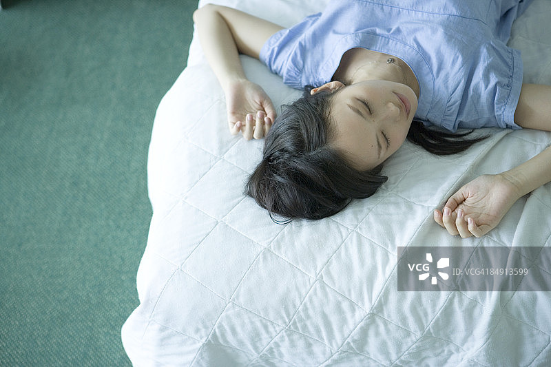 年轻女人在床上睡觉，高角度拍摄图片素材