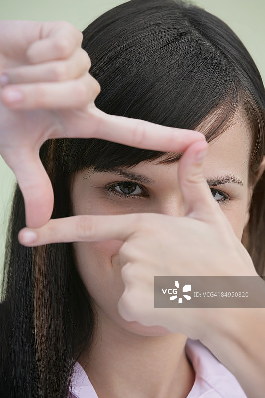 用手指做框架的年轻女子肖像图片素材