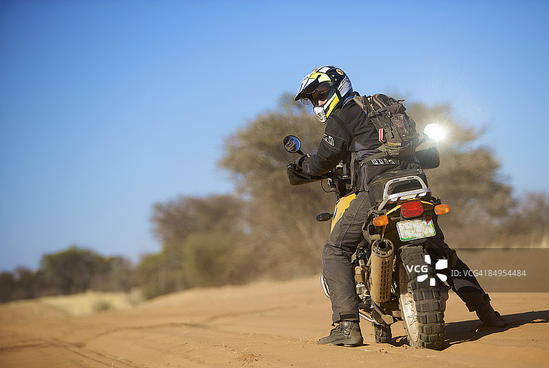 骑车人回头看，博茨瓦纳，卡拉哈里中部沙漠图片素材