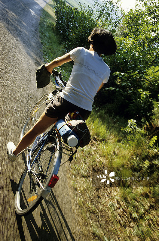 夏天，女人在乡村道路上骑自行车图片素材