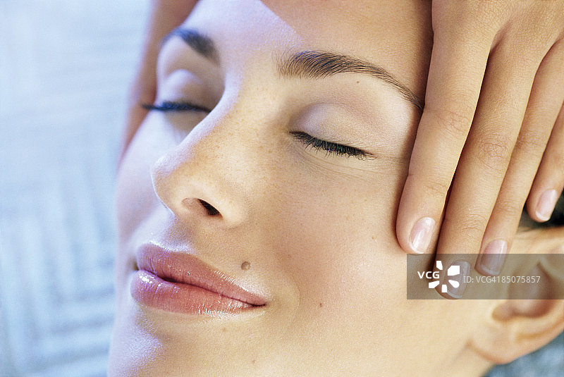 闭着眼睛享受面部按摩的微笑的女人图片素材