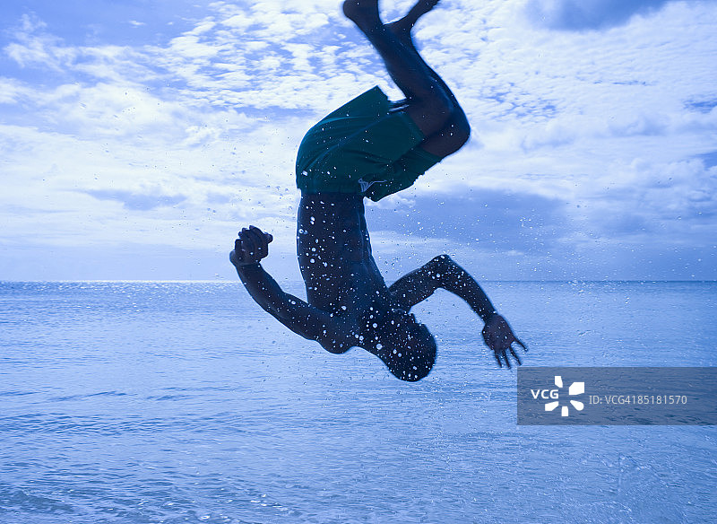 年轻男子在海滩上表演空翻图片素材