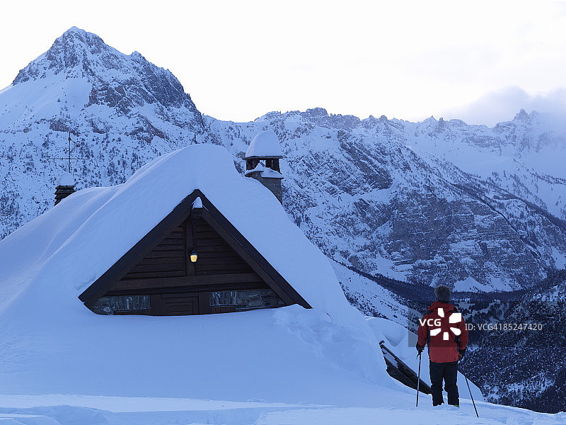 滑雪者走向亮着灯的山间小屋图片素材