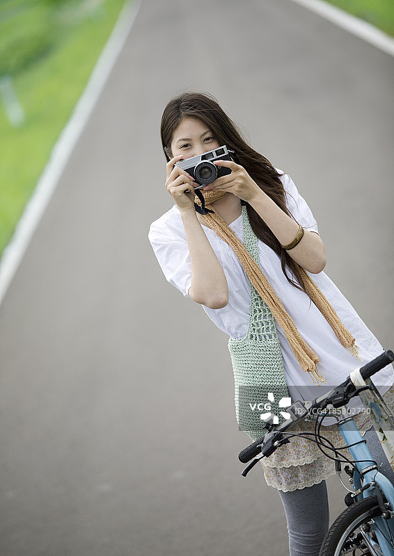 年轻女人在笔直的道路上拍照图片素材