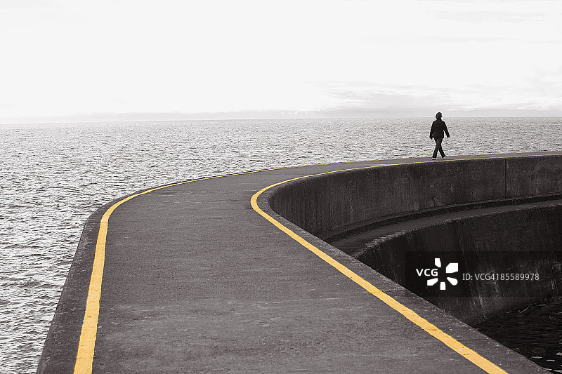 在海边长长的码头上行走的妇女图片素材