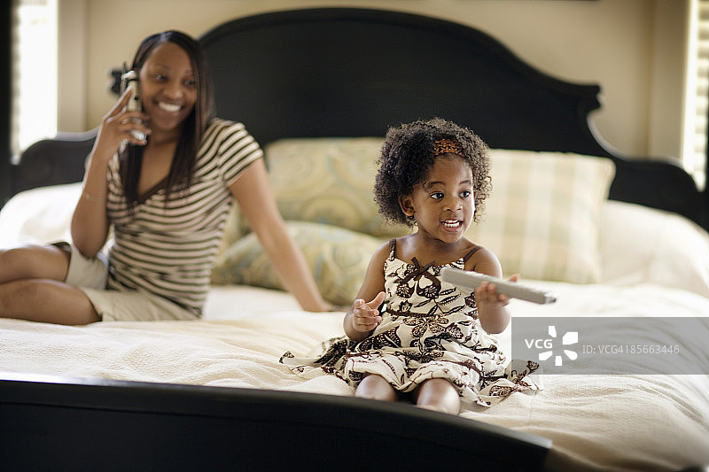年轻女孩看电视，妈妈在打电话图片素材