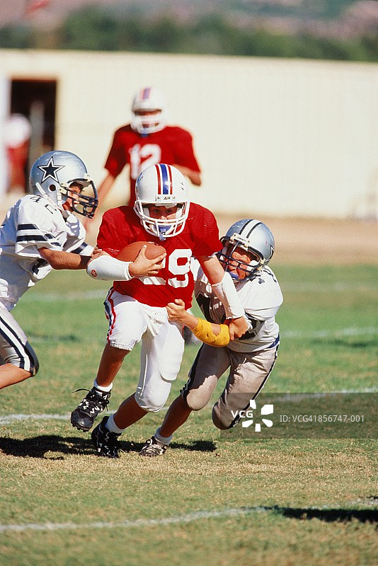 孩子们（11-13岁）玩美式橄榄球，两男孩擒抱对手图片素材