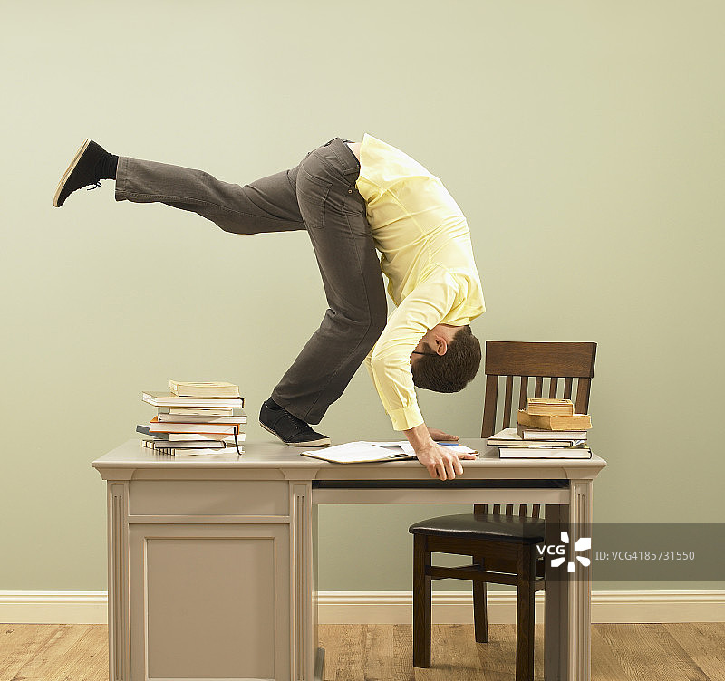 在桌子上表演前滚翻的年轻男人图片素材