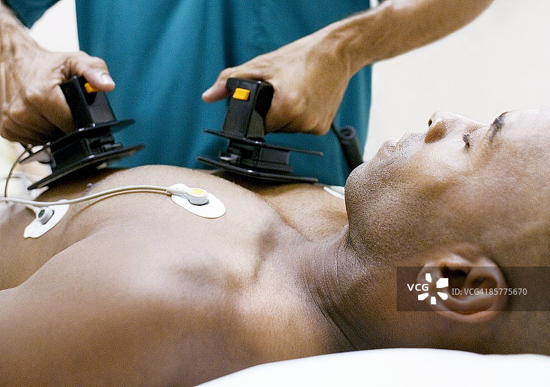 医生用除颤器电击男病人胸部图片素材