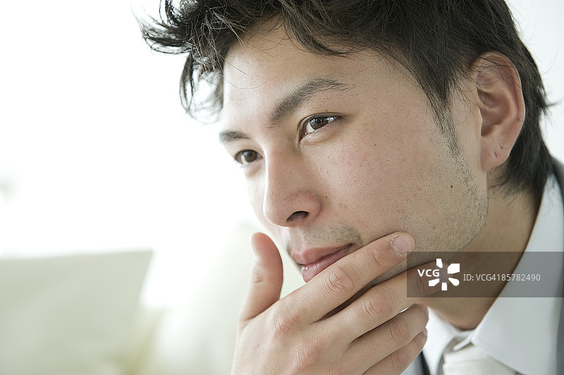 触摸下巴、看向远方的日本男人图片素材