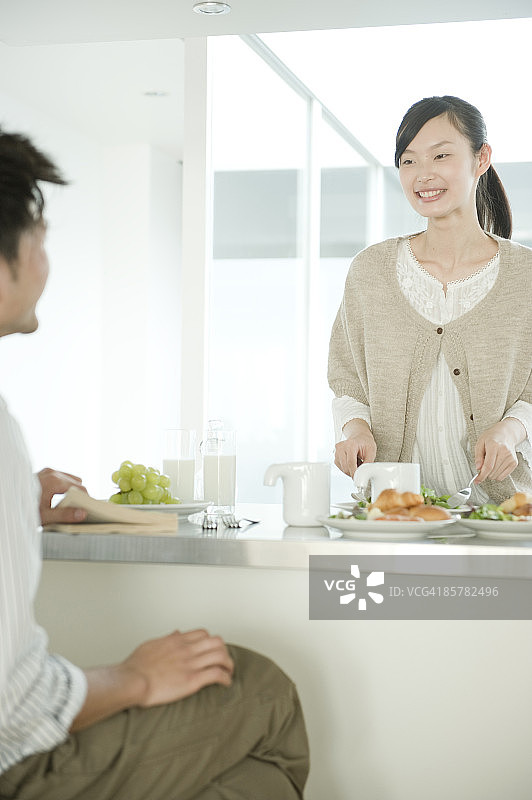 在厨房用餐微笑的年轻男女图片素材