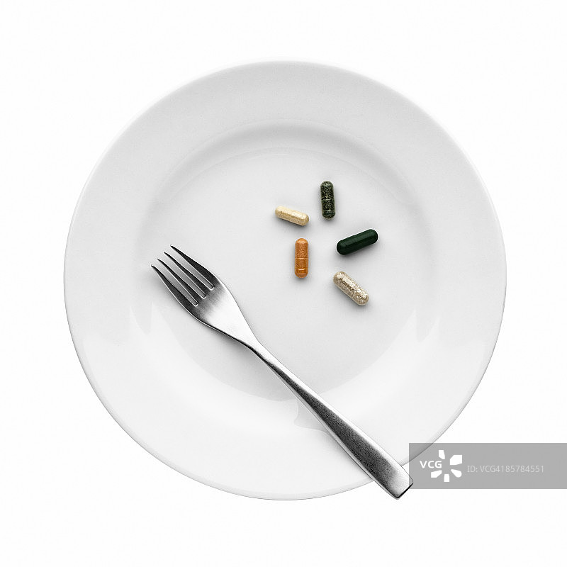 白色陶瓷盘和钢叉上的药丸图片素材