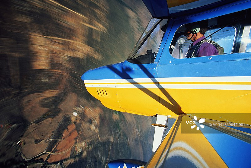 特技飞机、飞行员和飞机机头在模糊的田野上空图片素材