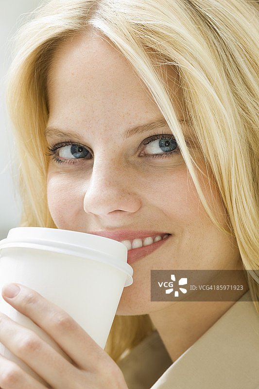 女人拿着外卖咖啡杯，面带微笑图片素材